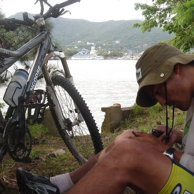 Leo Nardi Borba conferindo o mapa ao lado da bicicleta, à beira d'água